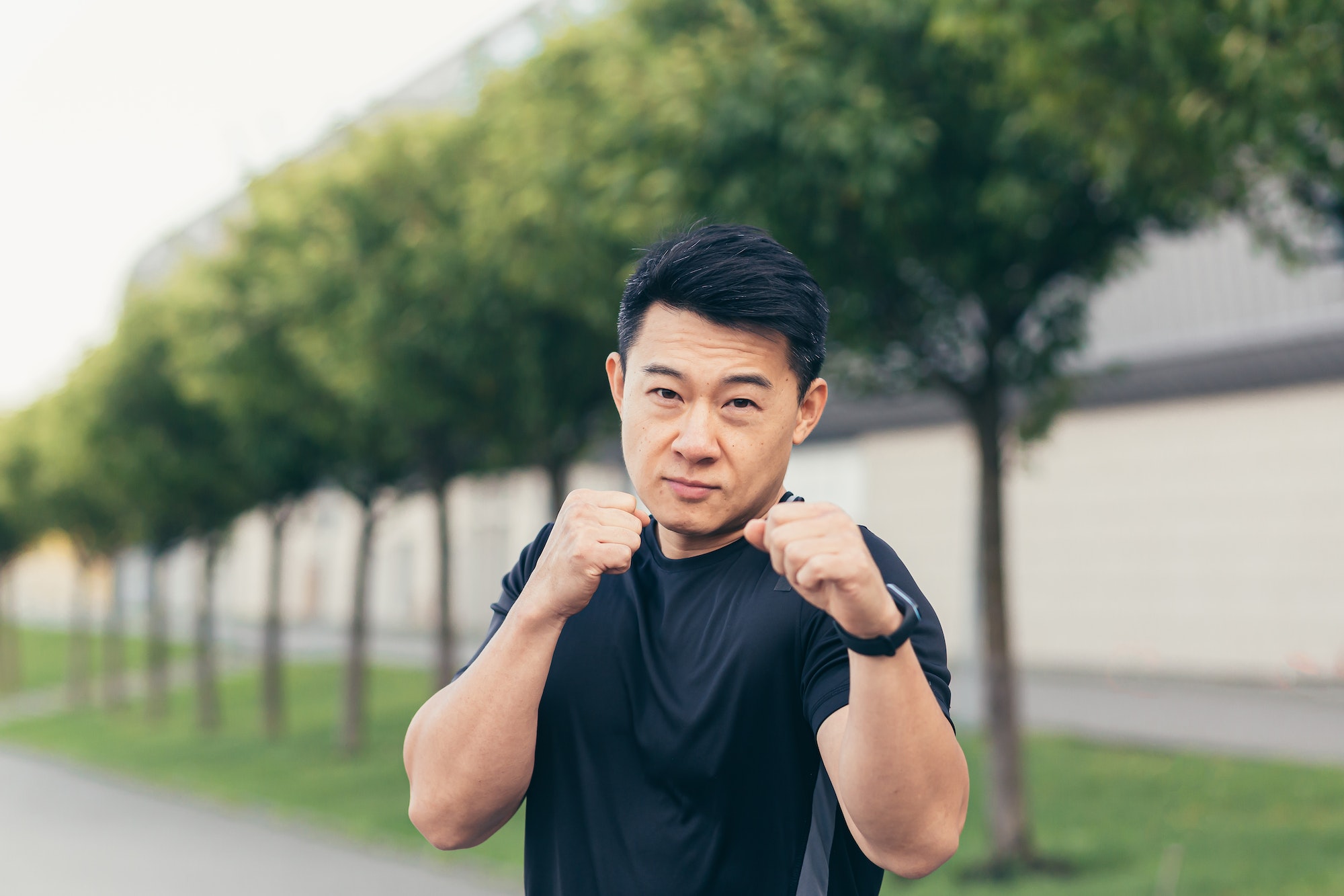 Male asian athlete demonstrates boxing rack during morning jogging and fitness