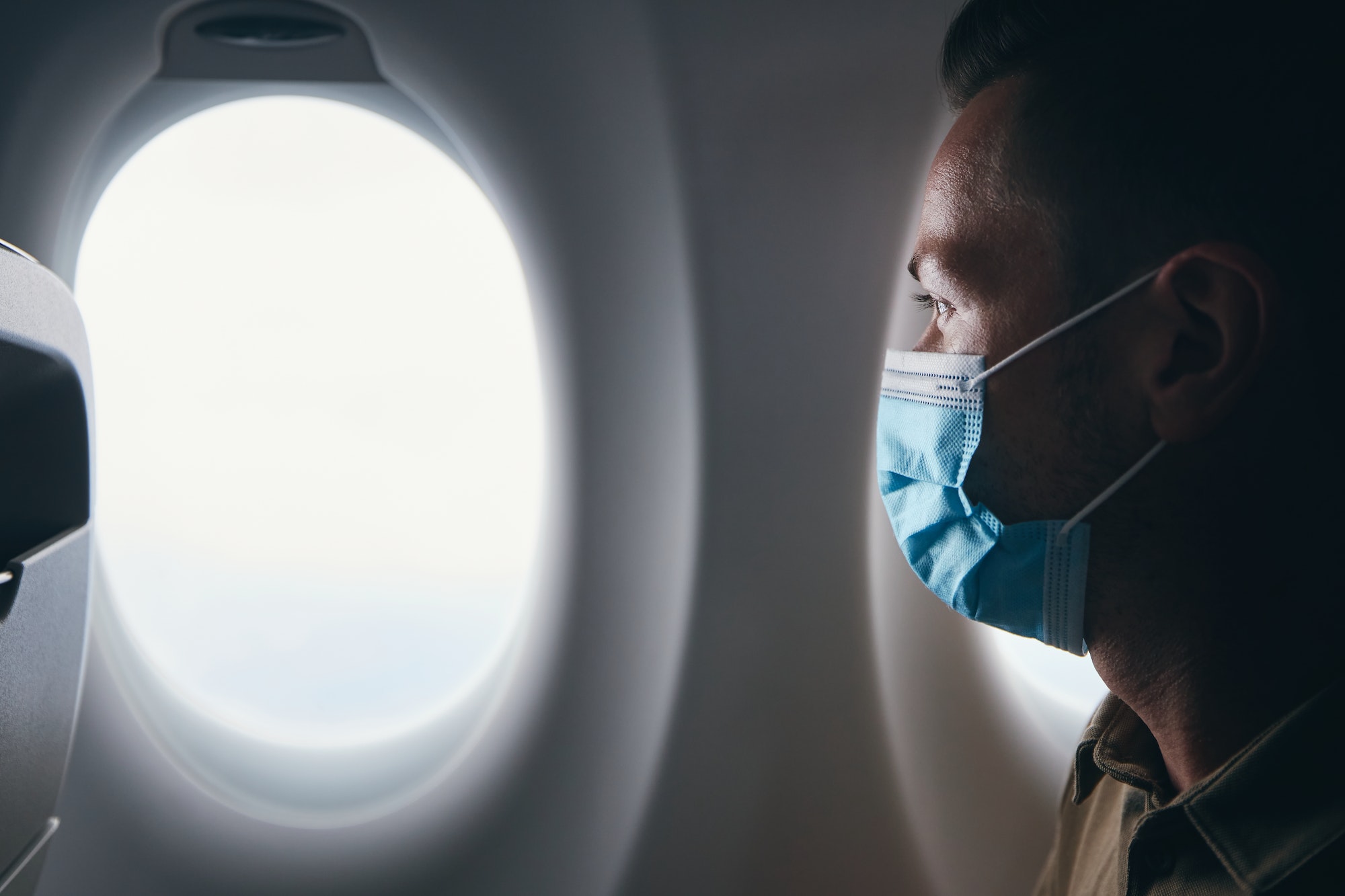 Man wearing face mask inside airplane during flight