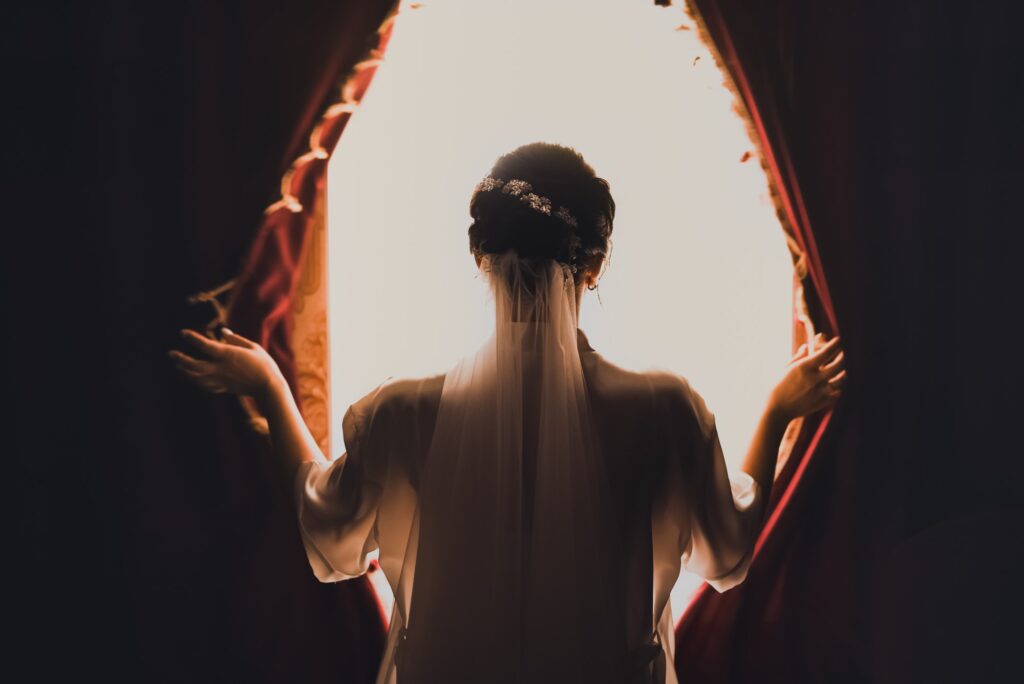 The bride opens the curtains on the huge white window